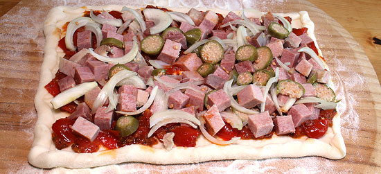 Pizzateig mit Tomaten und Rindszunge belegt