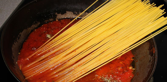 Rohe Spaghetti zu Sauce geben