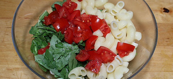 Rucola, Chifferi und Tomaten mit der Sauce vermischen