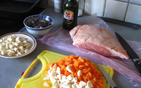 Schweinsschulter eingeschnitten, vorbereitetes Röstgemüse, Bier, Rosmarin.
