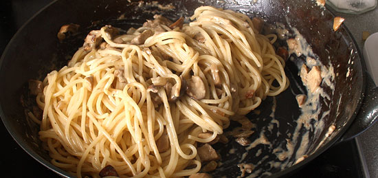 Spaghetti in der Pfanne mit der Sauce vermischen