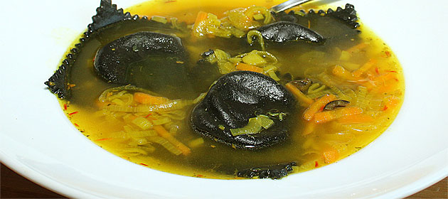 Ravioli al nero di seppia ripieni di baccalà in brodo allo zafferano